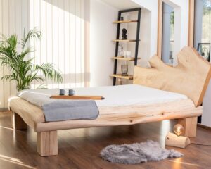 łóżko z dębu, ciekawe oparcie w łóżku, jasne duże łóżko małżeńskie, jasna pościel, lampka drewniana, komplet mebli do sypialni , kawa o poranku podana do łóżka, deska drewniana do serwowania, zielona roślina w sypialni, jasne duże okno w sypialni