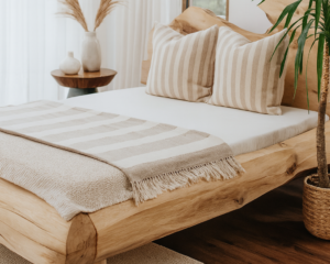 Ręcznie wykonane łóżko z litego drewna dębowego w stylu japandi, w jasnej i przytulnej sypialni z roślinami, lnianą pościelą i naturalnym oświetleniem — aranżacja Drewniane Klimaty.