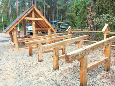 Drewniany stojak na rowery z bali w lesie, element małej architektury rekreacyjnej przy wiacie turystycznej